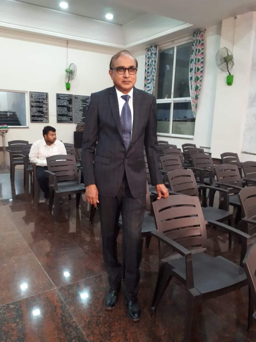 B.S. Kumaraswamy in formal suit inside a hall